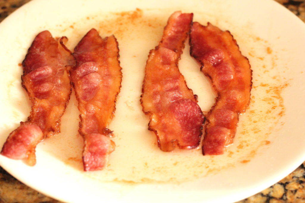 Image of bacon on a plate that has been cooked in the microwave. 