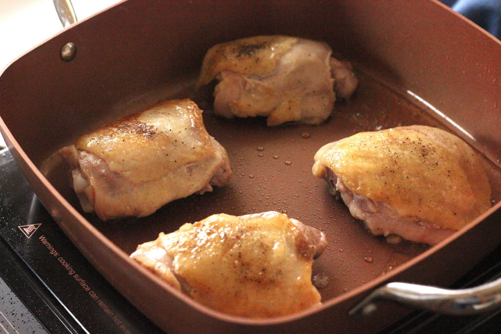 Browned chicken thighs in a copper pan