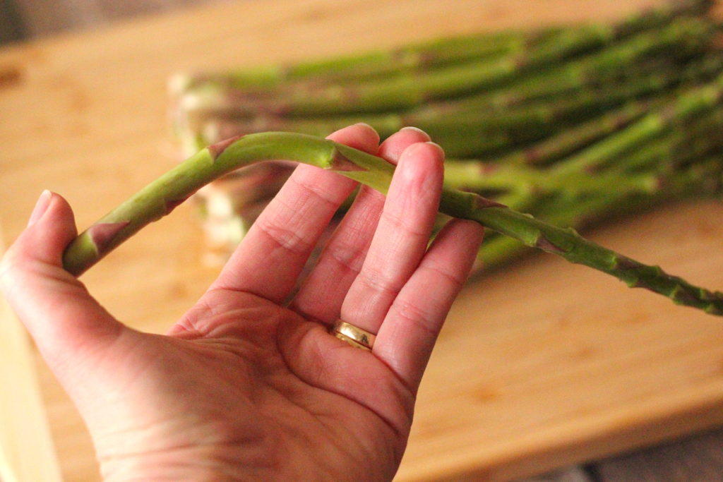 bending a sprig of asparagus in one hand to see where to cut