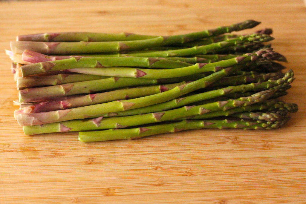 asparagus lined up on a cutting board