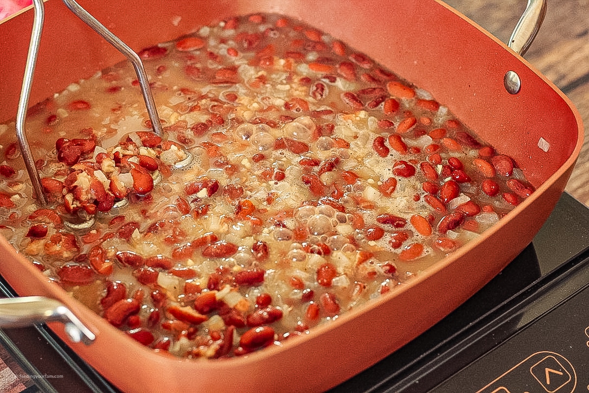 mashing refried beans with a potato masher