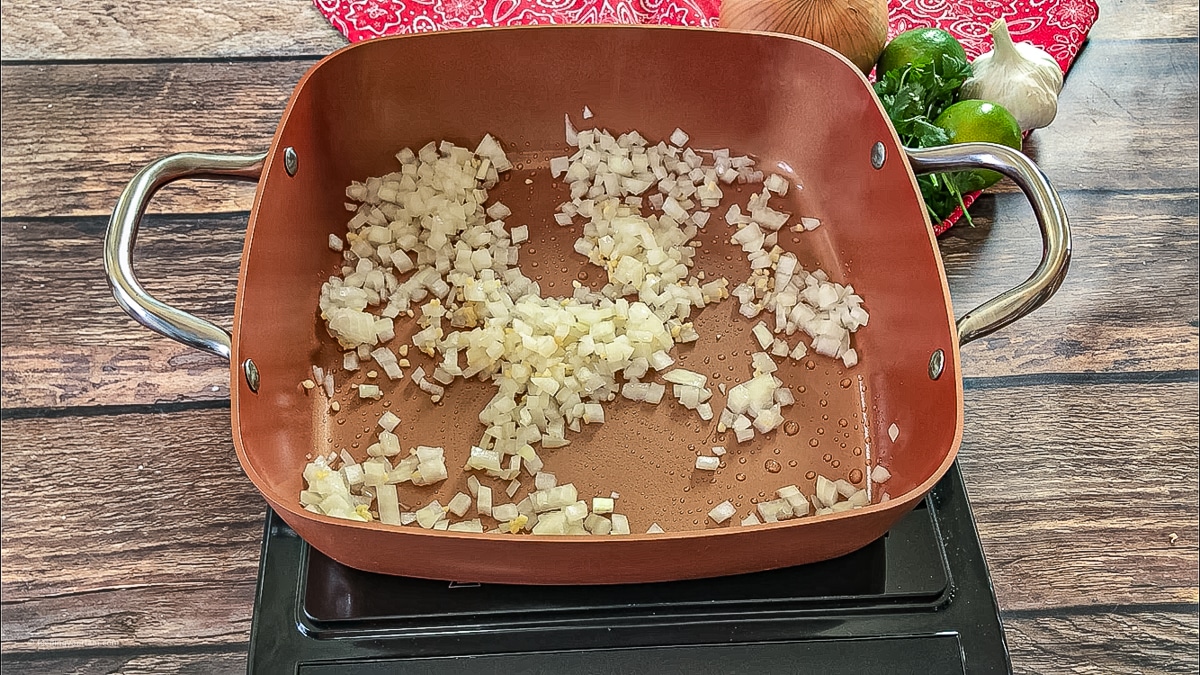 diced onions and garlic cooking in a pan