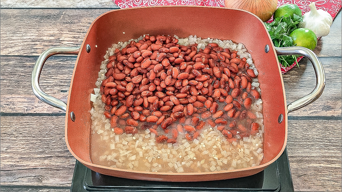 canned refried beans with cooked onions in a pan