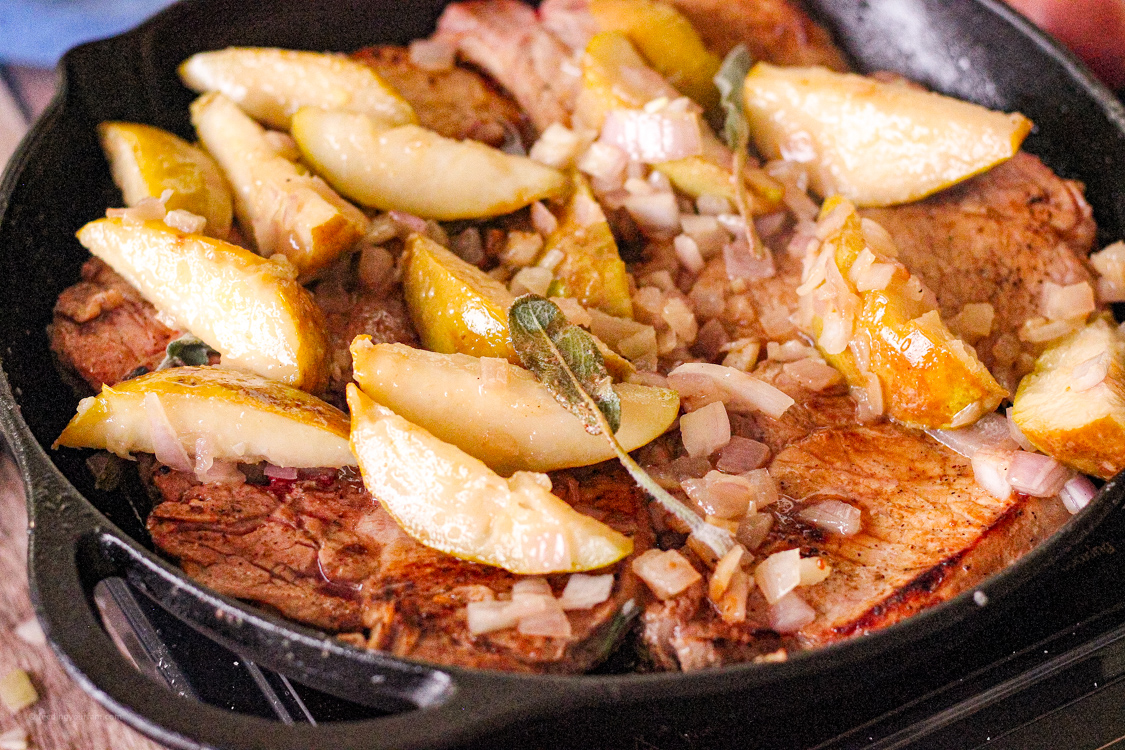 cooked pears and pork chops in a cast iron pan