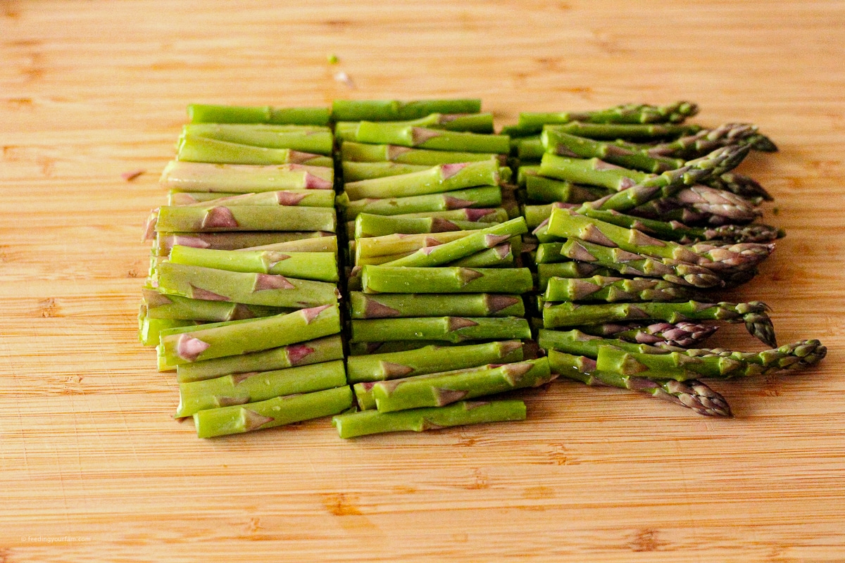 asparagus sliced into thirds on a wooden cutting board