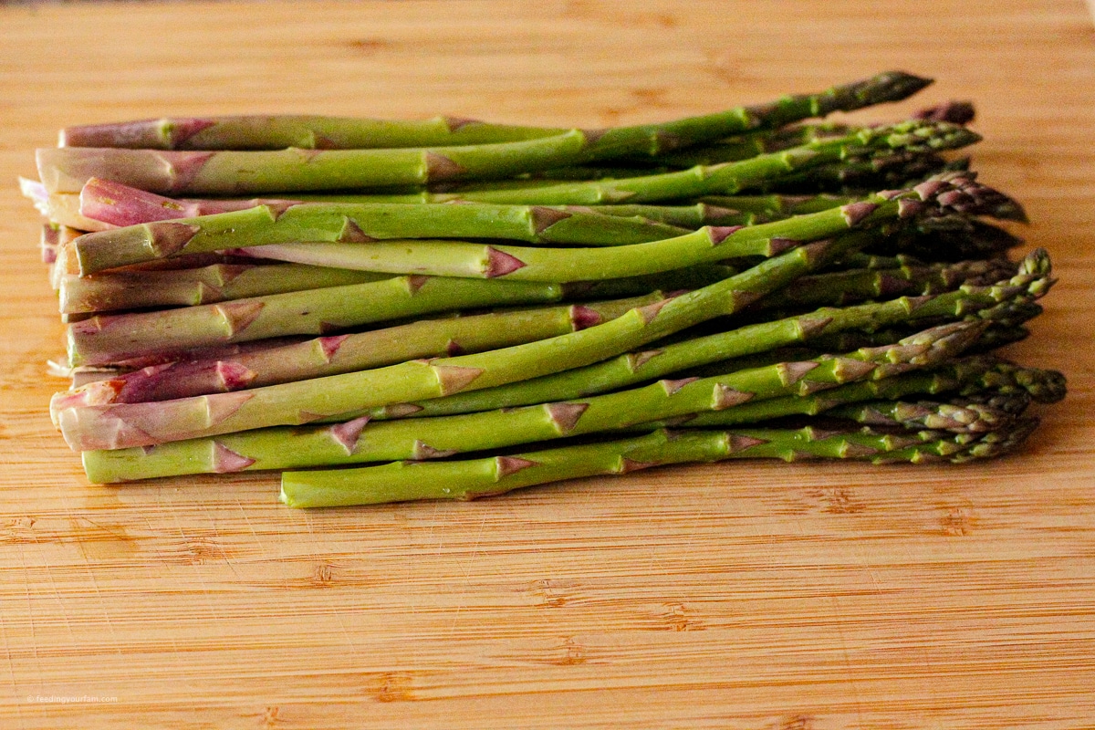 fresh asparagus spears on a wooden cutting board