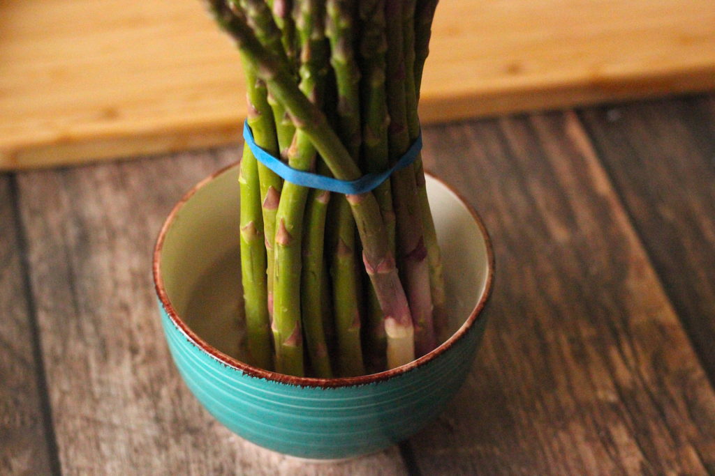 Bunch of asparagus standing in a small bowl of water