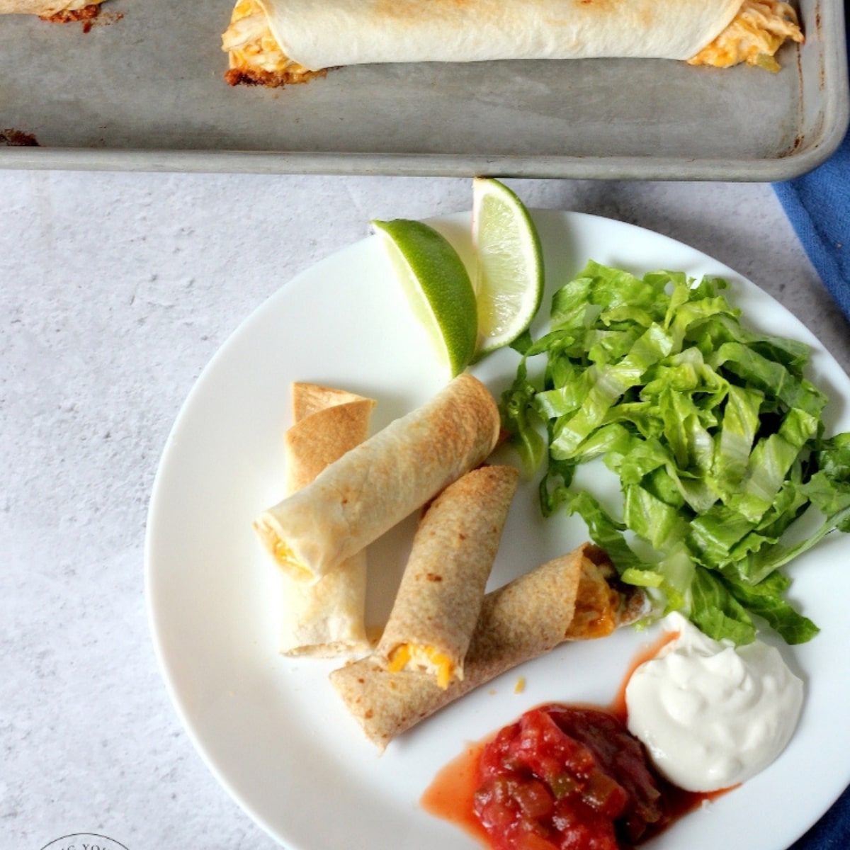 chicken taquitos on a plate with salsa and sour cream