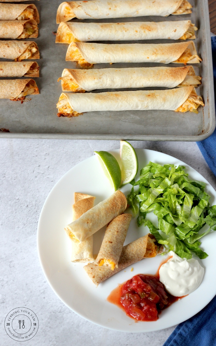 Cripsy oven baked chicken taquitos on a plate with salsa and sour cream