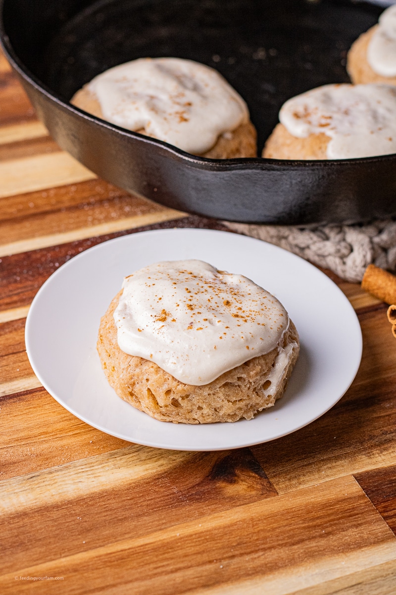 cinnamon biscuits with cream cheese frosting baked in a cast iron skillet