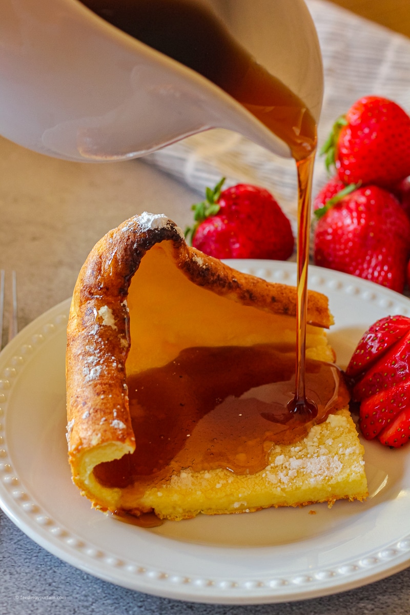 German Pancakes (also known as dutch baby pancakes) are a pan pancake that gets puffy and golden in the oven. This is a breakfast staple at our house! Easy to make, even the older kids can make this on their own! #germanpancakes #brunch #breakfast #dutchbaby #ovenpancake puffy pancake or German pancake slice with syrup