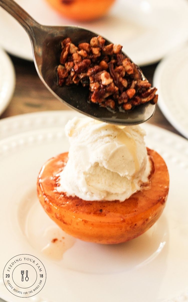 spooning toasted pecans over a caramelized peach topped with vanilla ice cream