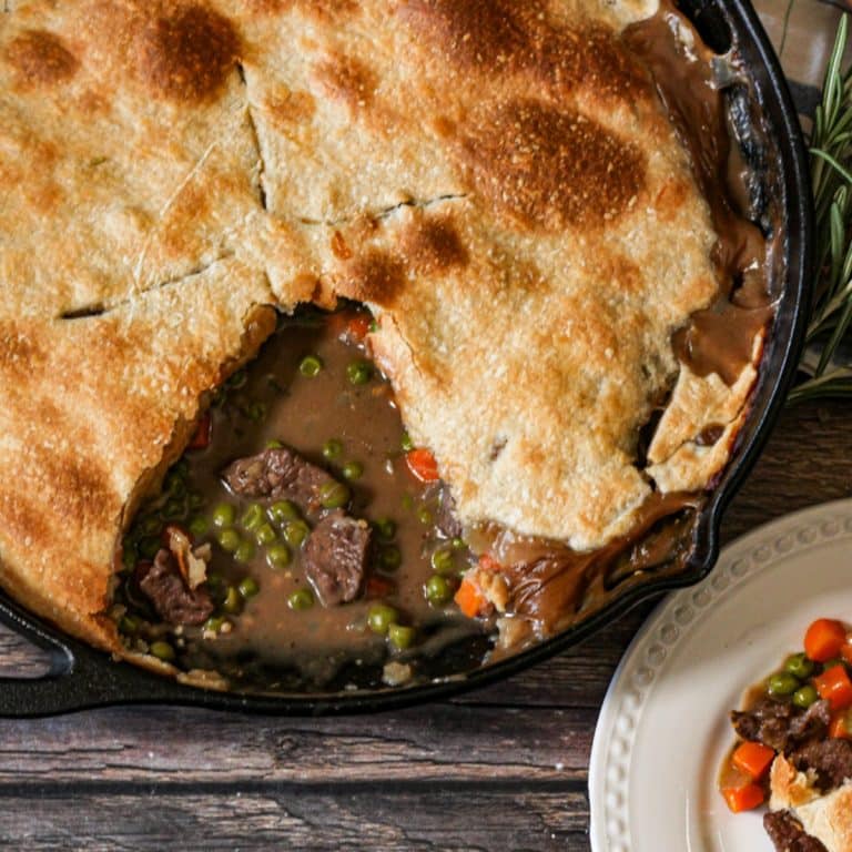 beef pot pie in a cast iron pan with a piece sliced out of it
