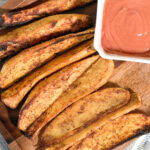 crispy air fried sweet potatoes on a wooden serving platter with dipping sauce