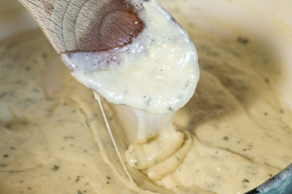 asiago cheese sauce on a wooden spoon