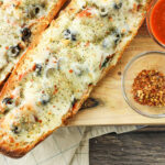 stuffed french bread pizza halves on a wooden platter
