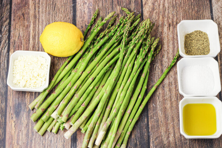 asparagus with bowls of pepper, salt, olive oil, feta cheese and a lemon