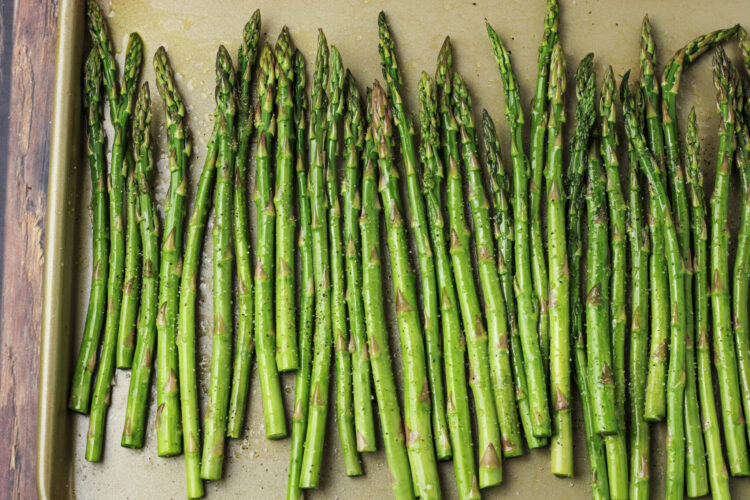 asparagus spears seasoned on a baking sheet