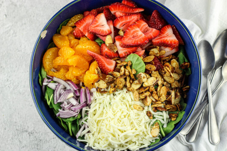 blue salad bowl with spinach, strawberries, mozzarella, toasted almonds, red onion and mandarin oranges