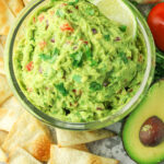 guacamole surrounded by chips and avocado
