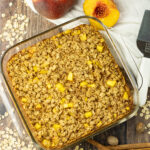 pan of baked oatmeal surrounded by dry oatmeal, peaches and cinnamon sticks