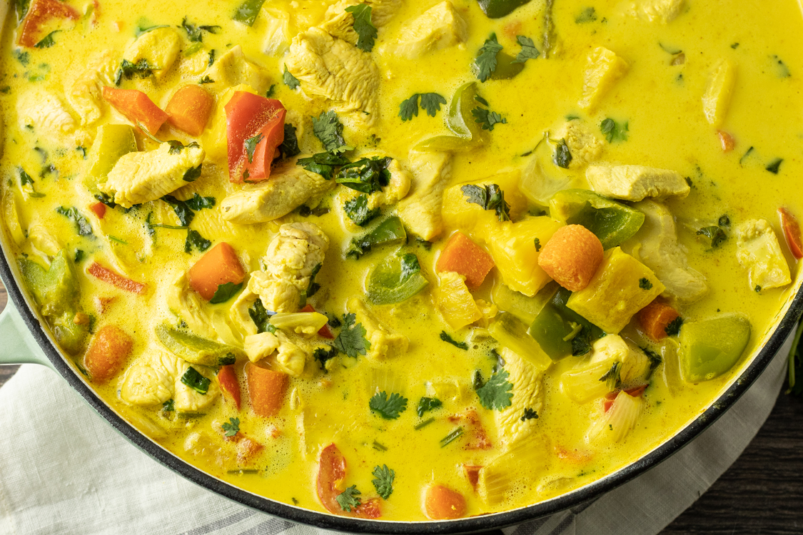 pot of yellow curry with pineapples, carrots, peppers and chicken
