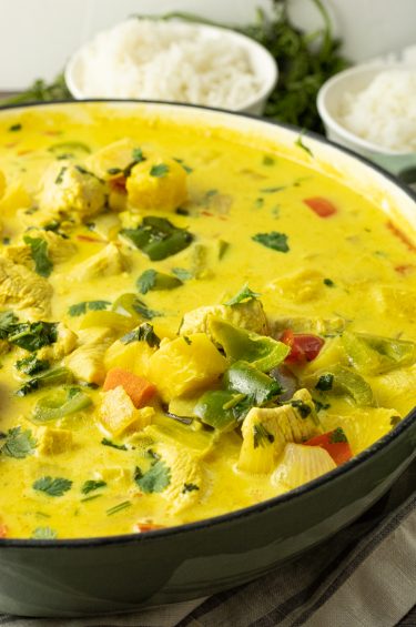 big pan of pineapple curry with green peppers, onions, chicken, red peppers and pineapple in a yellow curry sauce