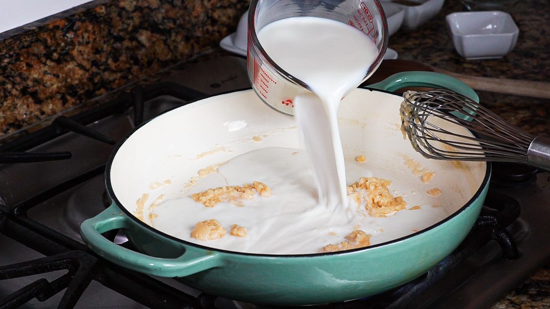pouring milk into a pan to make a roux