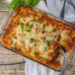 lasagna made with ravioli in a baking dish with some scooped out with a spoon