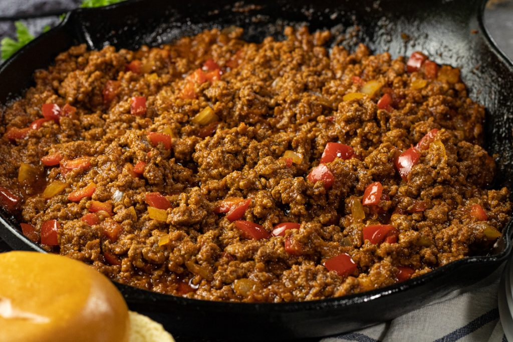 ground beef with onions and red peppers in a tomato sauce to make easy sloppy joes