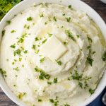 big bowl of mashed potatoes topped with butter and parsley