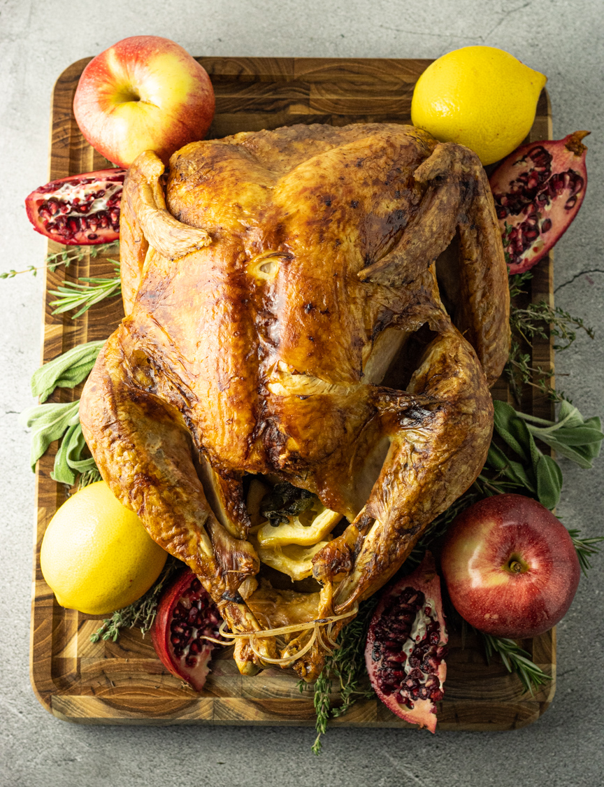 baked turkey surrounded by lemons, pomegranates, spices and apples