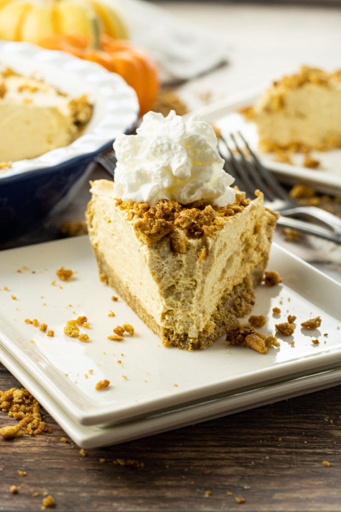 slice of pumpkin cream pie on a white plate with a bite taken out of the pie