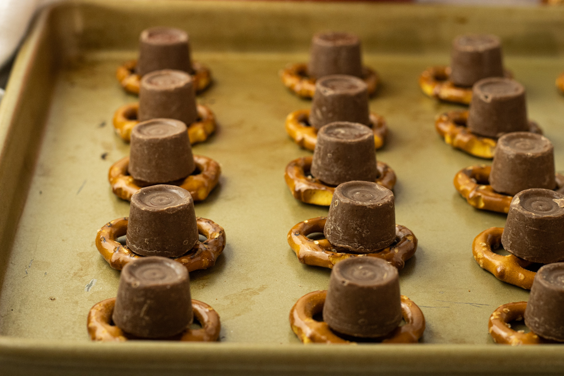 Rolo candy on top of pretzels on a baking sheet