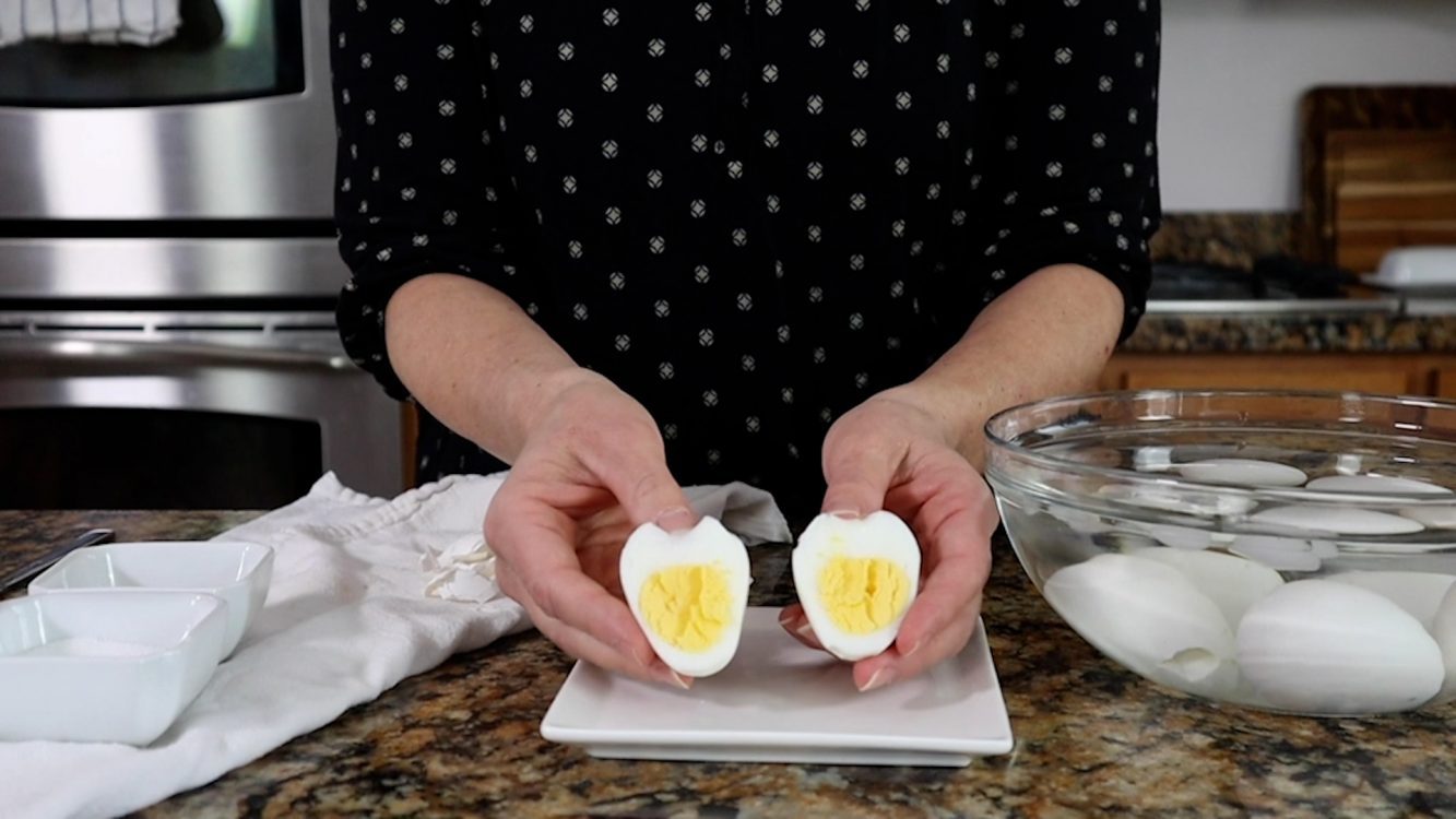 holding a sliced, cooked hard boiled egg