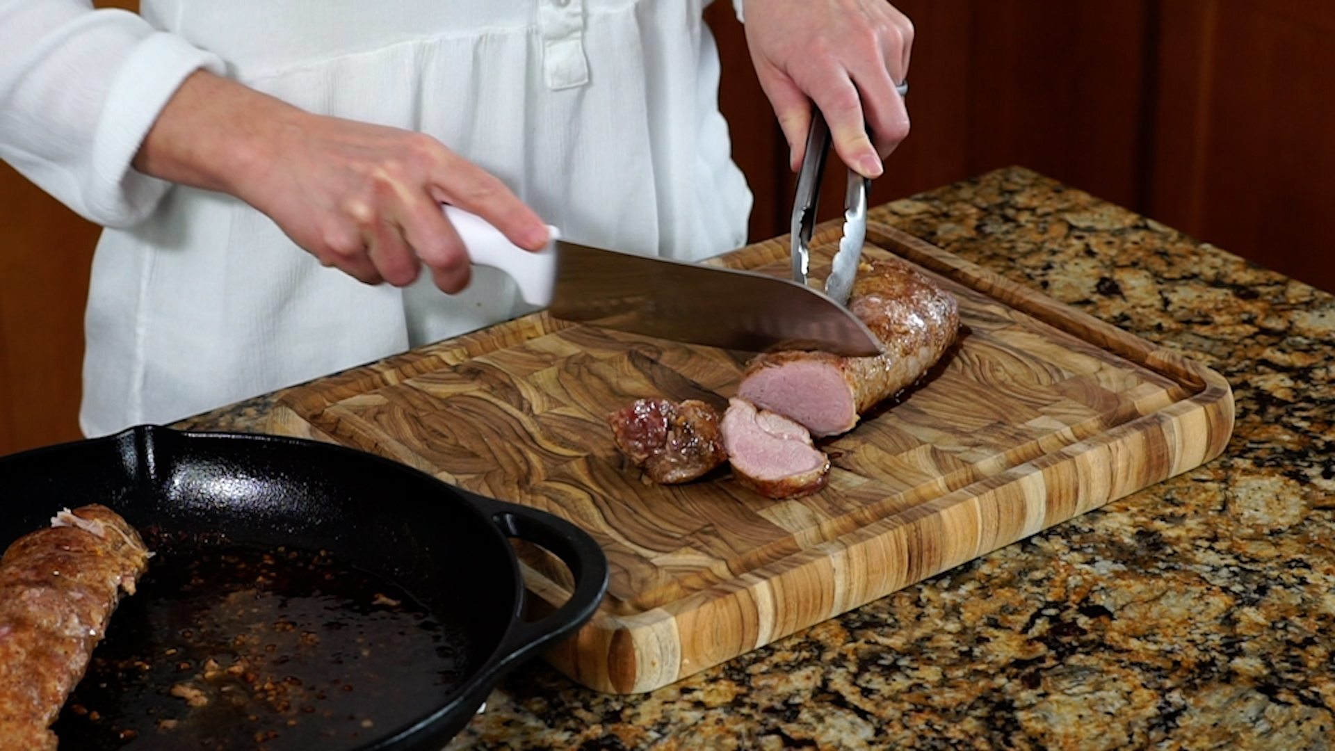 slicing a pork tenderloin on a wooden cutting board