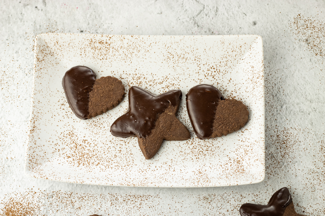 chocolate dipped cookies in heart and star shapes on a white plate