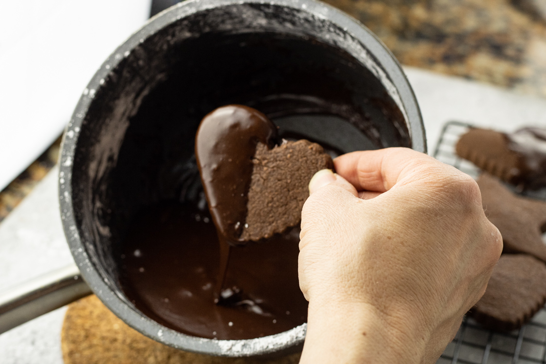 dipping a chocolate cookie into chocolate glaze