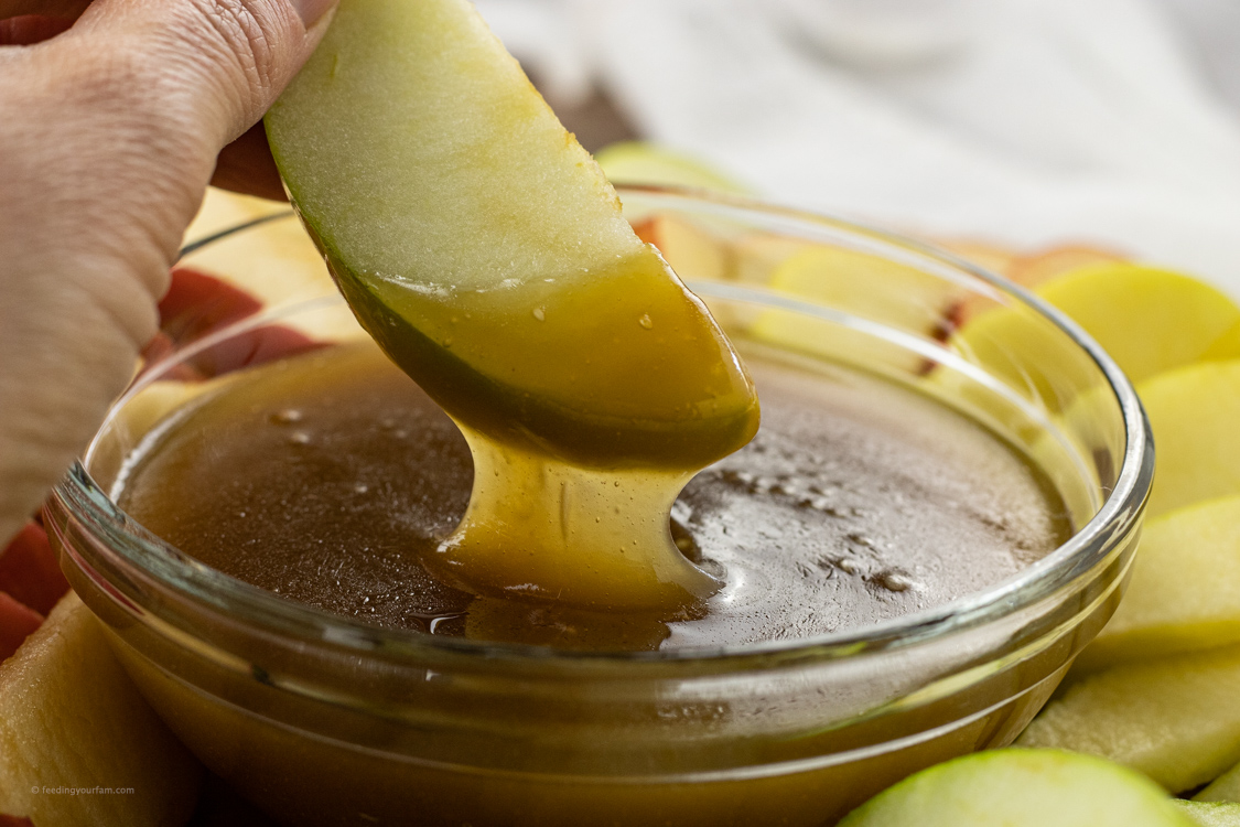 dipping an apple slice in caramel