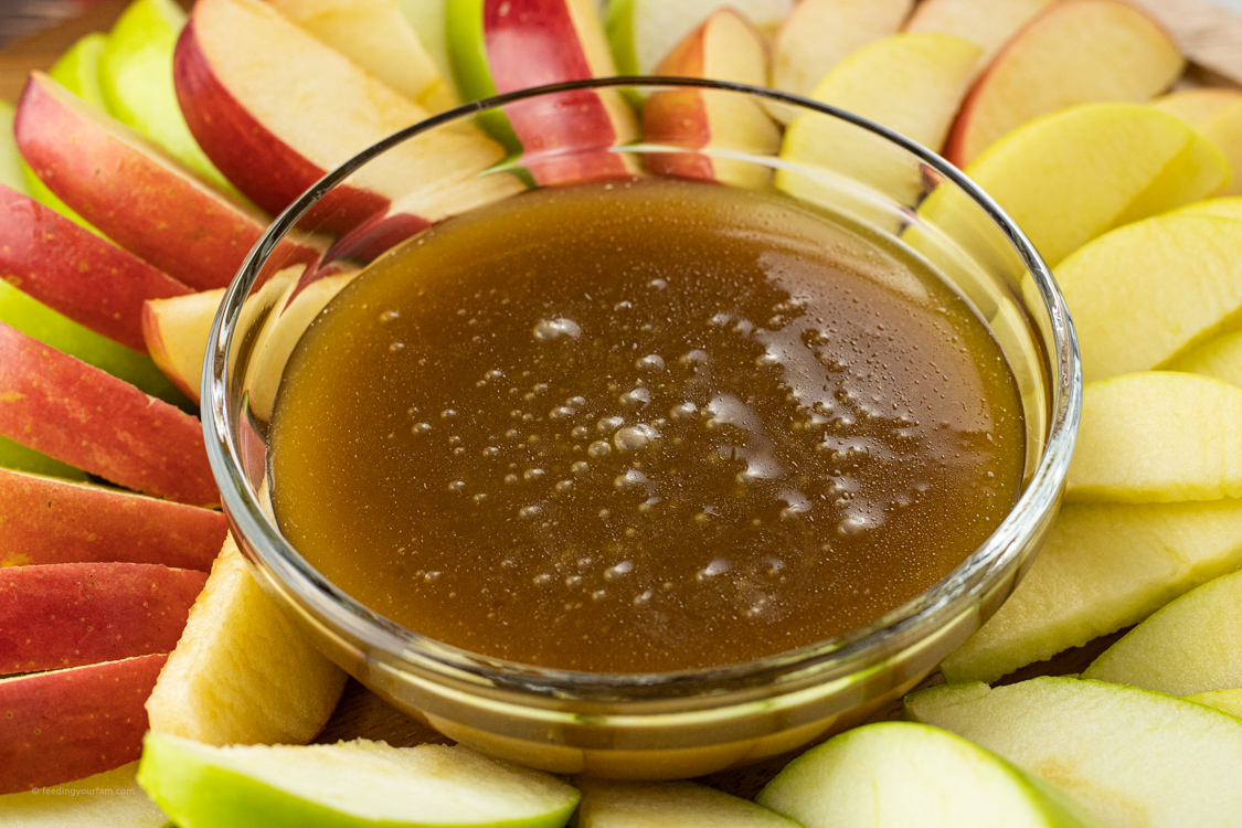 bowl of caramel sauce surrounded by sliced apples