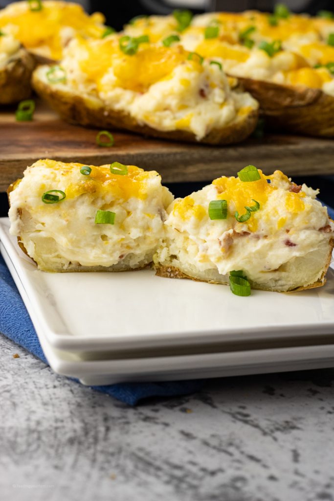 twice baked potato sliced in half on a white plate