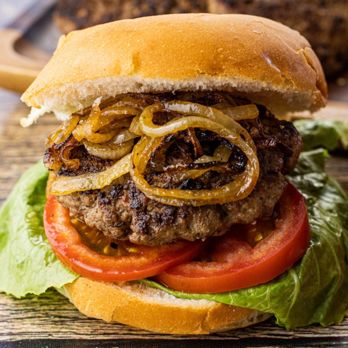 hamburger in a bun with cooked onions and tomatoes