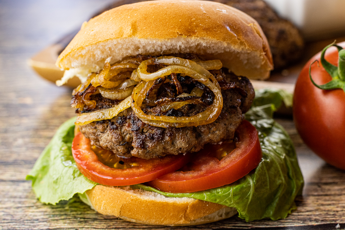 hamburger with tomatoes, lettuce and grilled onions