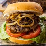 hamburger with fried onions, tomato and lettuce on a bun