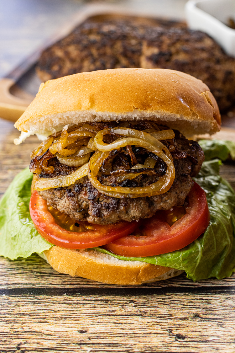 hamburger with fried onions, tomato and lettuce on a bun