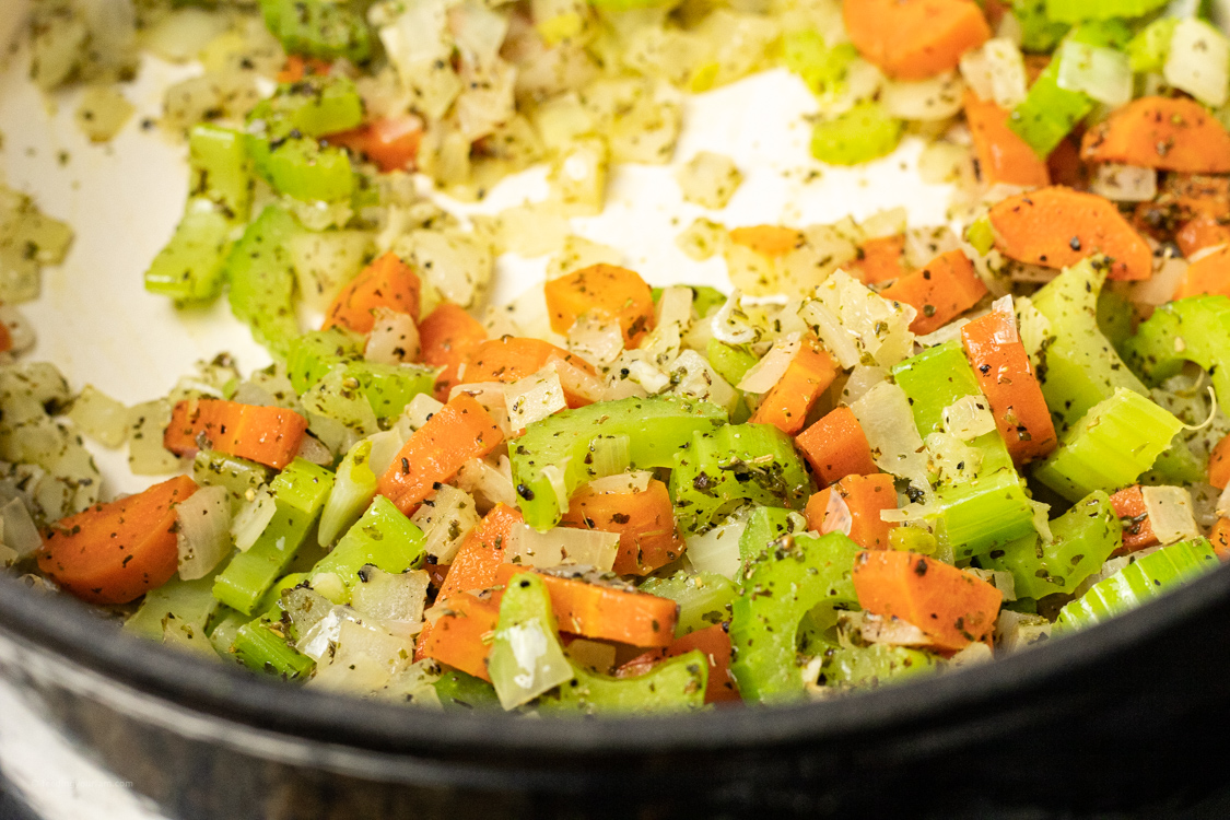 carrots, celery and onions in the bottom of an enameled cast iron pot