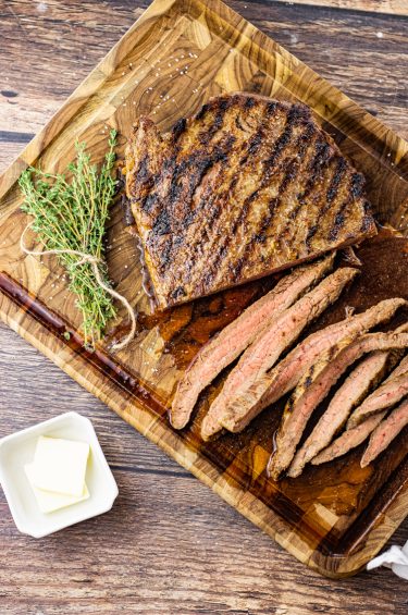 sliced flank steak on a wooden cutting board