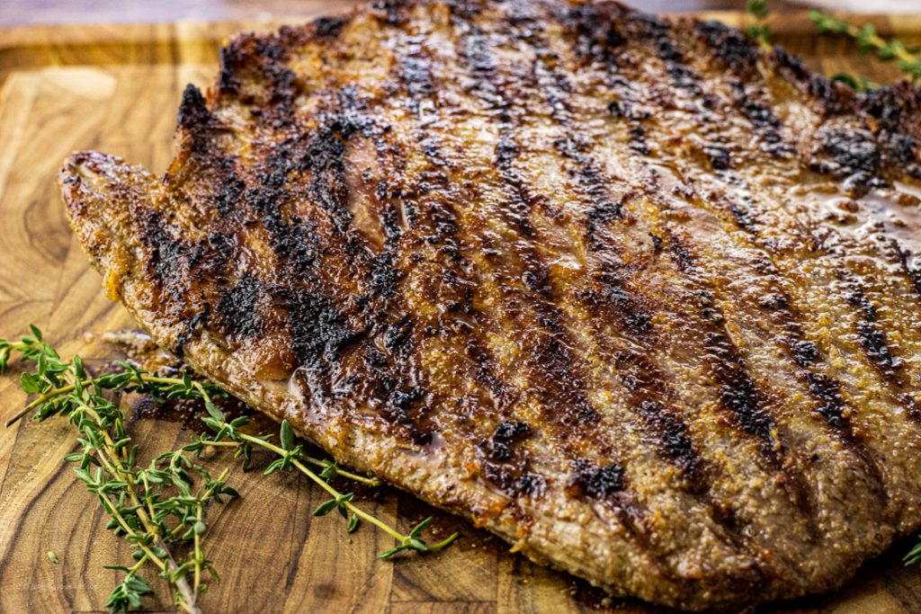 flank steak with grill lines on a wooden cutting board