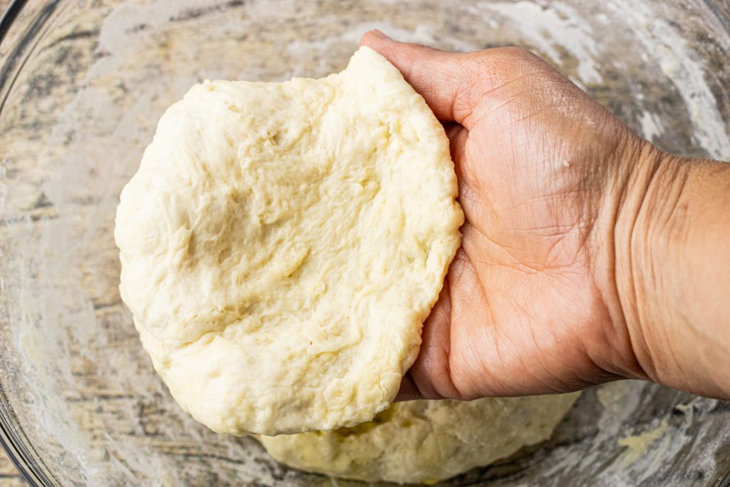 hand holding a piece of dough to make fried bread