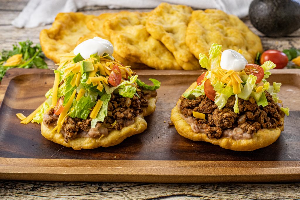 scones topped with taco meat, lettuce, cheese, tomatoes and sour cream